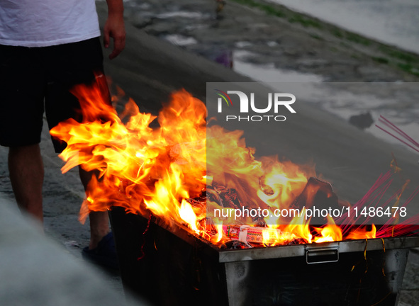 People are burning paper money to offer sacrifices to their ancestors during the Hungry Ghost Festival in Yichang, China, on August 16, 2024...