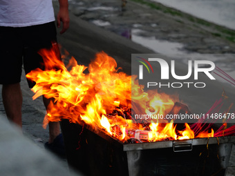 People are burning paper money to offer sacrifices to their ancestors during the Hungry Ghost Festival in Yichang, China, on August 16, 2024...