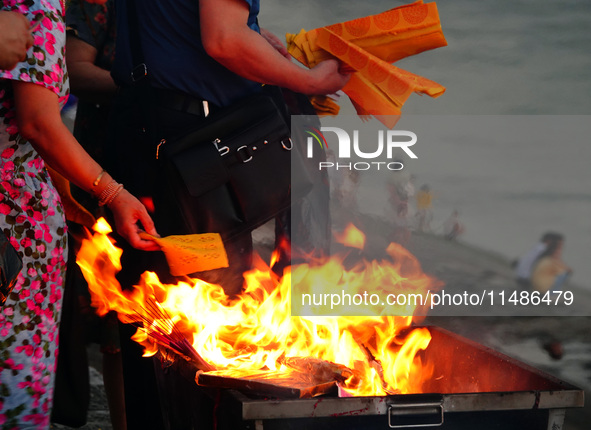 People are burning paper money to offer sacrifices to their ancestors during the Hungry Ghost Festival in Yichang, China, on August 16, 2024...