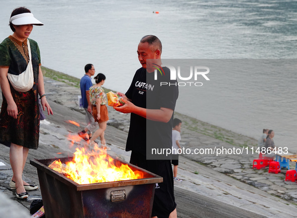 People are burning paper money to offer sacrifices to their ancestors during the Hungry Ghost Festival in Yichang, China, on August 16, 2024...