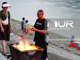 People are burning paper money to offer sacrifices to their ancestors during the Hungry Ghost Festival in Yichang, China, on August 16, 2024...