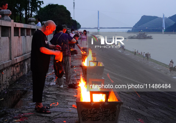 People are burning paper money to offer sacrifices to their ancestors during the Hungry Ghost Festival in Yichang, China, on August 16, 2024...