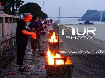 People are burning paper money to offer sacrifices to their ancestors during the Hungry Ghost Festival in Yichang, China, on August 16, 2024...