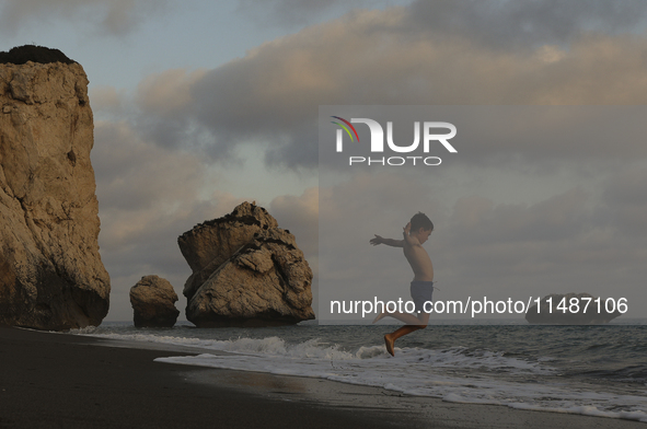 A boy jumps as a wave approaches while relaxing on Aphrodite's Rock ''Petra tou Romiou'', the place where, according to ancient Greek mythol...