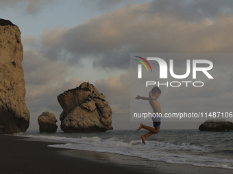 A boy jumps as a wave approaches while relaxing on Aphrodite's Rock ''Petra tou Romiou'', the place where, according to ancient Greek mythol...