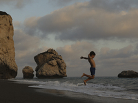 A boy jumps as a wave approaches while relaxing on Aphrodite's Rock ''Petra tou Romiou'', the place where, according to ancient Greek mythol...