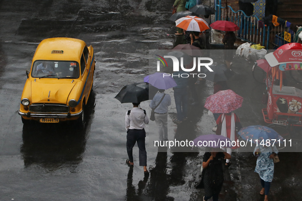 People are holding umbrellas and standing at a bus stop following heavy monsoon rains in Kolkata, West Bengal, India, on August 17, 2024. 