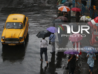 People are holding umbrellas and standing at a bus stop following heavy monsoon rains in Kolkata, West Bengal, India, on August 17, 2024. (