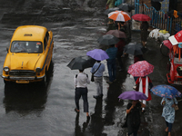 People are holding umbrellas and standing at a bus stop following heavy monsoon rains in Kolkata, West Bengal, India, on August 17, 2024. (