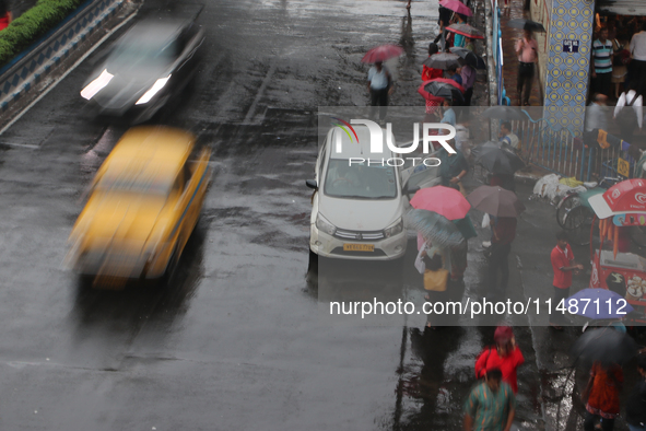 People are holding umbrellas and standing at a bus stop following heavy monsoon rains in Kolkata, West Bengal, India, on August 17, 2024. 