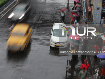 People are holding umbrellas and standing at a bus stop following heavy monsoon rains in Kolkata, West Bengal, India, on August 17, 2024. (