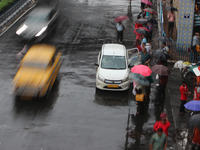 People are holding umbrellas and standing at a bus stop following heavy monsoon rains in Kolkata, West Bengal, India, on August 17, 2024. (