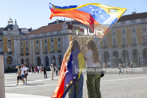 People are holding the Venezuelan flag and protesting the recent election results in Venezuela during a rally at Commerce Square in Lisbon,...