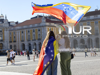 People are holding the Venezuelan flag and protesting the recent election results in Venezuela during a rally at Commerce Square in Lisbon,...