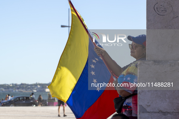 A person is holding a Venezuelan flag to protest the recent election results in Venezuela during a rally at Commerce Square in Lisbon, Portu...