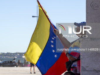 A person is holding a Venezuelan flag to protest the recent election results in Venezuela during a rally at Commerce Square in Lisbon, Portu...