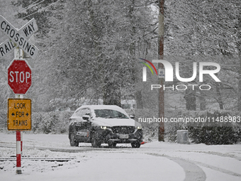 A car is driving on a snow-covered road during heavy snowfall in Springfield, in the Selwyn District of Canterbury, in the South Island, New...