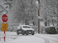 A car is driving on a snow-covered road during heavy snowfall in Springfield, in the Selwyn District of Canterbury, in the South Island, New...