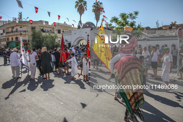 A devotee from a Sufi order in traditional Tunisian dress is representing the city's patron saint on horseback and leading the annual proces...