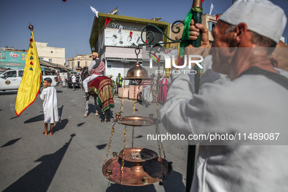 A devotee from a Sufi order in traditional Tunisian dress is representing the city's patron saint on horseback and leading the annual proces...