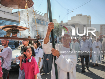 A devotee from a Sufi order in traditional Tunisian dress is carrying a Sufi flag with burning incense as he is leading the annual processio...