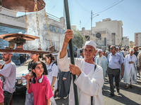 A devotee from a Sufi order in traditional Tunisian dress is carrying a Sufi flag with burning incense as he is leading the annual processio...