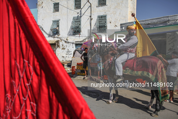 A devotee from a Sufi order in traditional Tunisian dress is representing the city's patron saint on horseback and leading the annual proces...