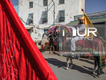 A devotee from a Sufi order in traditional Tunisian dress is representing the city's patron saint on horseback and leading the annual proces...