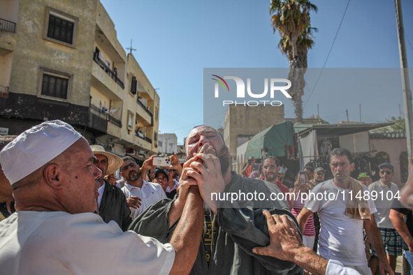 A follower of a Sufi order is swallowing pieces of glass while in a state of trance during the annual procession of Sidi Bou Said in Ariana,...