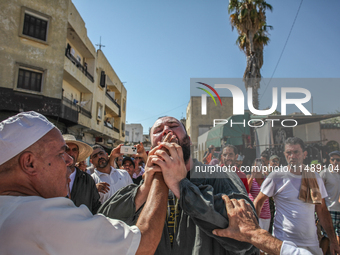 A follower of a Sufi order is swallowing pieces of glass while in a state of trance during the annual procession of Sidi Bou Said in Ariana,...