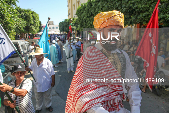 A devotee from a Sufi order in traditional Tunisian dress is representing the city's patron saint on horseback and leading the annual proces...