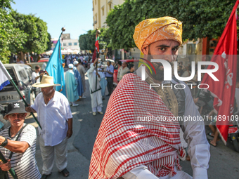 A devotee from a Sufi order in traditional Tunisian dress is representing the city's patron saint on horseback and leading the annual proces...