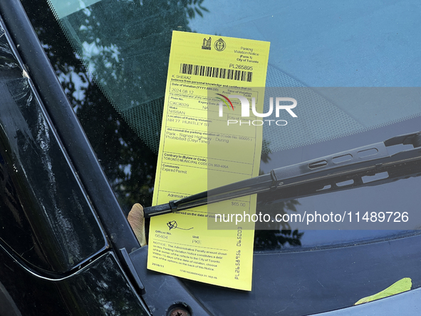 A parking ticket is being affixed to the windshield of a vehicle in downtown Toronto, Ontario, Canada, on August 14, 2024. 