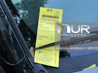 A parking ticket is being affixed to the windshield of a vehicle in downtown Toronto, Ontario, Canada, on August 14, 2024. (