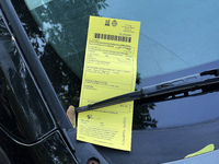 A parking ticket is being affixed to the windshield of a vehicle in downtown Toronto, Ontario, Canada, on August 14, 2024. (