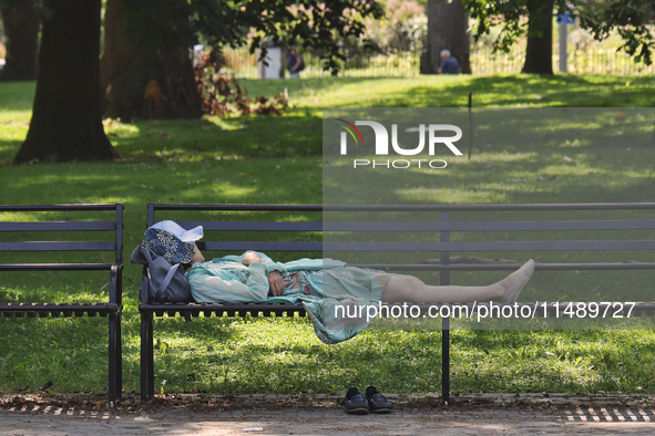 A person is taking an afternoon nap on a park bench at Queens Park in Toronto, Ontario, Canada, on August 14, 2024. 