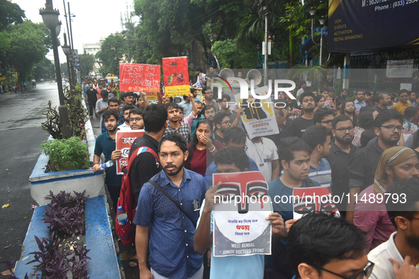 Doctors are holding posters and marching on the street during a protest condemning the rape and murder of a trainee medic at a government-ru...