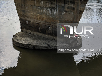 A young boy is sitting on the pillar of a bridge as he is catching fish in Sopore, Jammu and Kashmir, India, on August 18, 2024. (