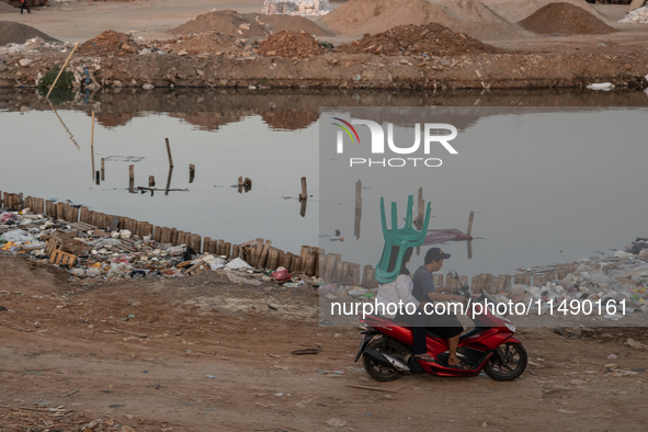 A woman is carrying a chair while riding on a motorcycle in Jakarta, Indonesia, on August 18, 2024. 