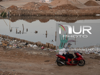 A woman is carrying a chair while riding on a motorcycle in Jakarta, Indonesia, on August 18, 2024. (