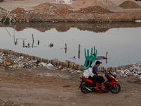 A woman is carrying a chair while riding on a motorcycle in Jakarta, Indonesia, on August 18, 2024. (