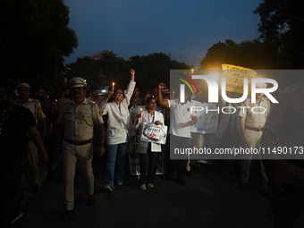 Medical professionals and students are holding lit candles and shouting slogans in a protest march demanding justice following the rape and...