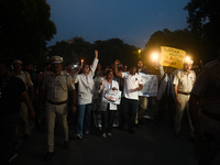 Medical professionals and students are holding lit candles and shouting slogans in a protest march demanding justice following the rape and...