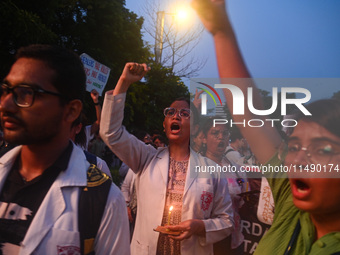 Medical professionals and students are holding lit candles and shouting slogans in a protest march demanding justice following the rape and...