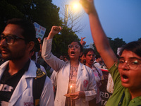 Medical professionals and students are holding lit candles and shouting slogans in a protest march demanding justice following the rape and...