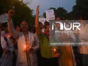 Medical professionals and students are holding lit candles and shouting slogans in a protest march demanding justice following the rape and...