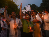 Medical professionals and students are holding lit candles and shouting slogans in a protest march demanding justice following the rape and...