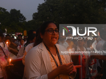 Medical professionals and students are holding lit candles and shouting slogans in a protest march demanding justice following the rape and...