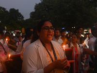 Medical professionals and students are holding lit candles and shouting slogans in a protest march demanding justice following the rape and...