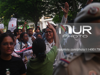 Medical professionals and students are shouting slogans in a protest march demanding justice following the rape and murder of a trainee medi...